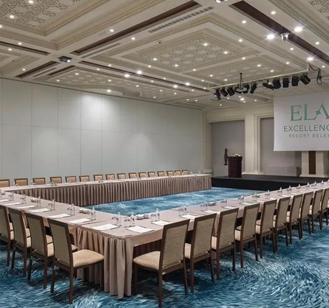 Meeting room set up in a U-shape with name cards, water bottles, a stage and a lectern at a resort hotel in Belek