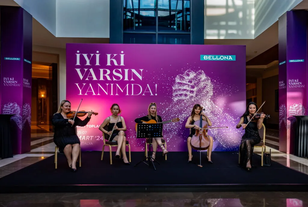 String quartet performing in front of an illuminated “İyi ki Varsın Yanımda” backdrop at a Bellona event, Türkiye